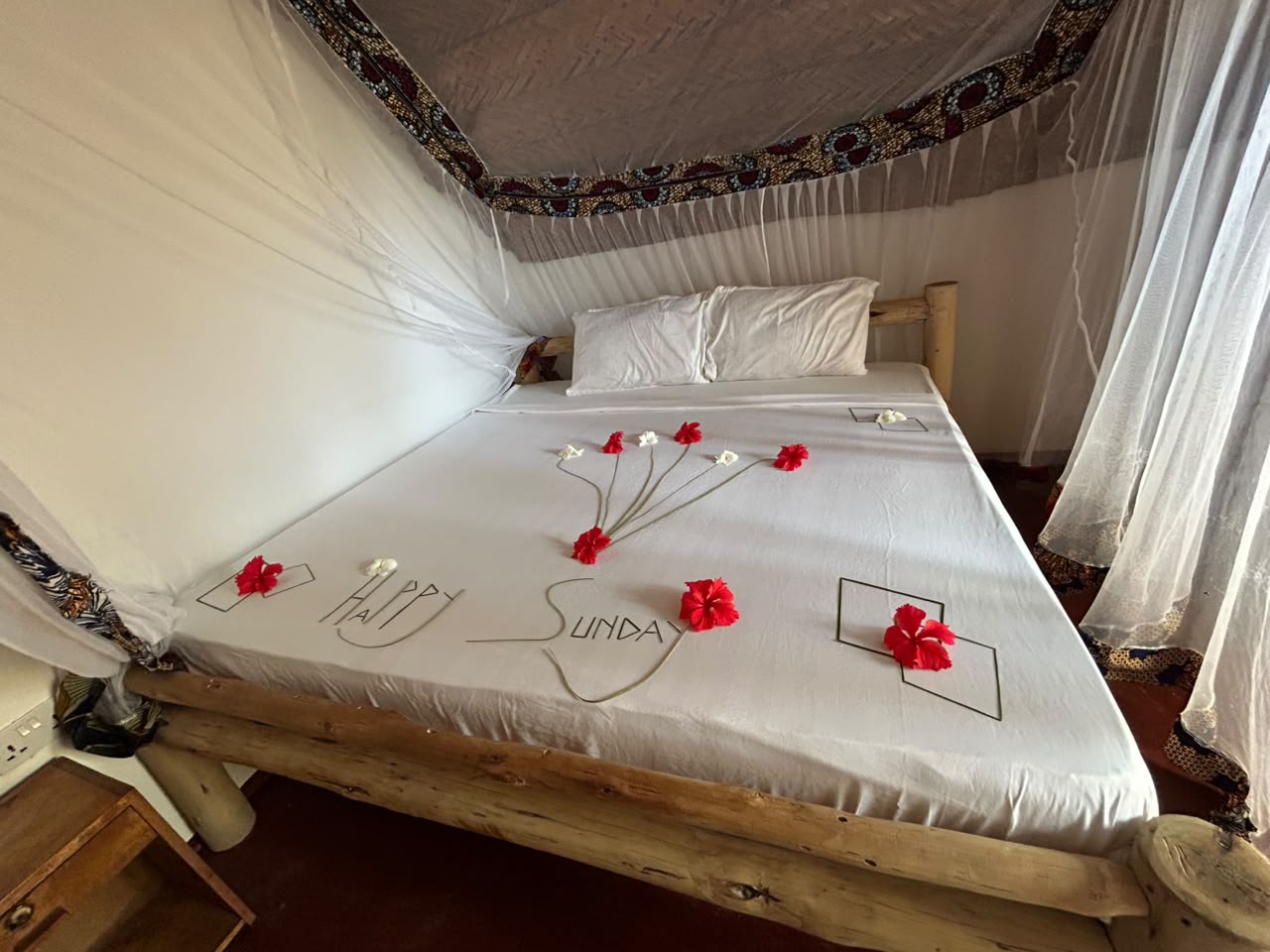 Canopy bed inside the Makuti Banda dressed with hibiscus flowers