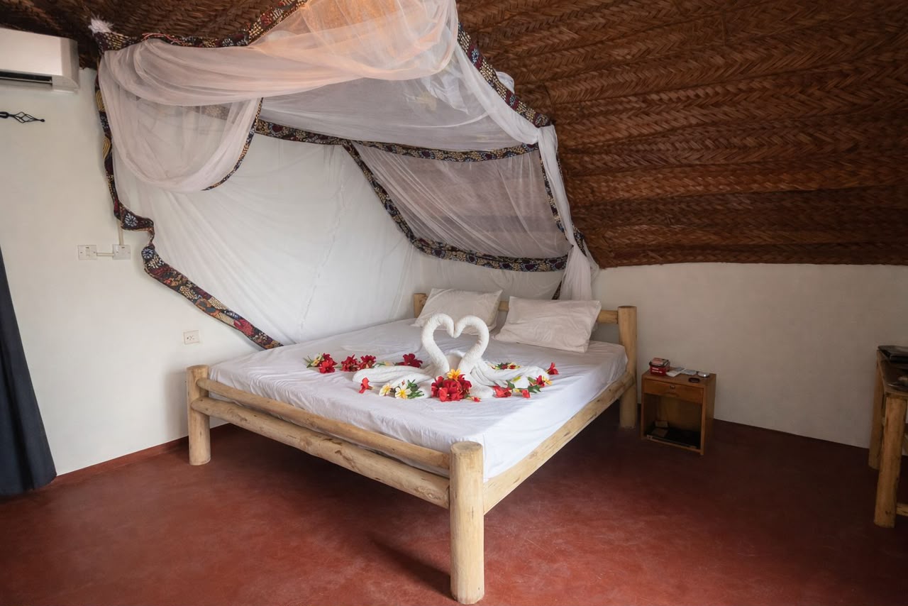 Bedroom inside the Makuti Banda with rustic wooden bed and mosquito net